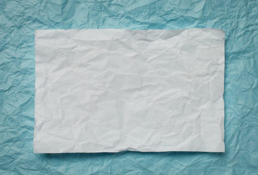 Crumpled  white paper card on cyan  background, place for tex