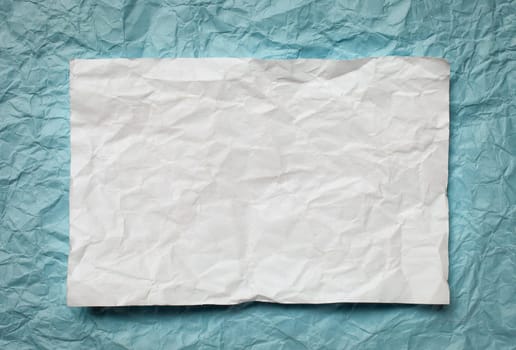 Crumpled  white paper card on cyan  background, place for tex