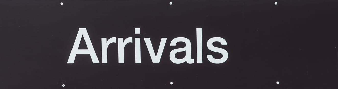 Black sign with white text showing Arrivals