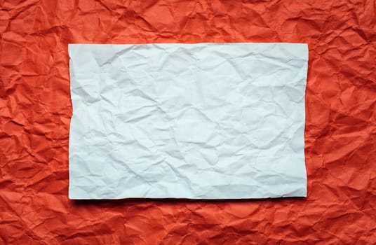 Crumpled  white paper card on red background, place for tex