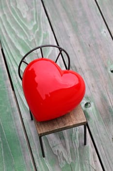 heart on small toy chair, grunge wood background