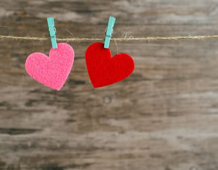 two  hearts hanging on a cord on a wooden background, love background