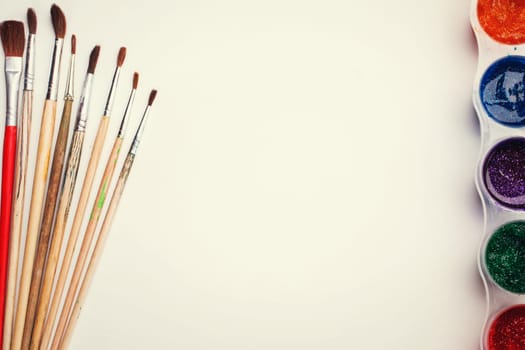 Frame pictures wits copyspace composition painting tools on white sheet of paper on wooden board