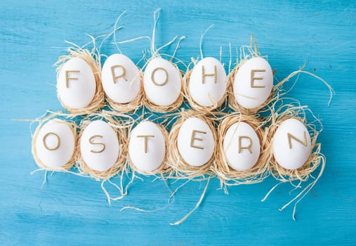 Huehnereier with Happy Easter lettering on blue background