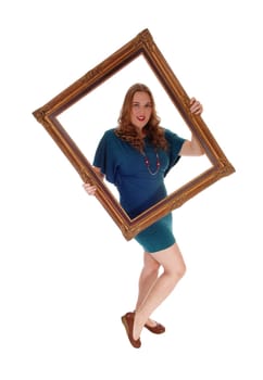 A blond woman in a dress standing isolated for white background, holding.a picture frame and looking trough..
