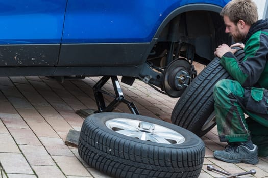 Young man swapping car tyres. From summer tyres to winter tyres on his car..