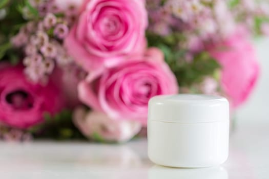 A cream can stands on the table,in the background a great bouquet of flowers that unfolds its beauty. wonderful rose tones are on the table