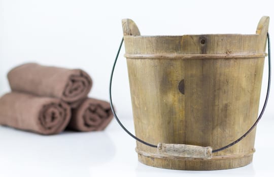 A wooden bucket in close-up,towels in the background,a detail for the sauna