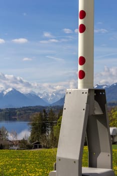 A railway barrier in spring,in the background the mountains and a lake