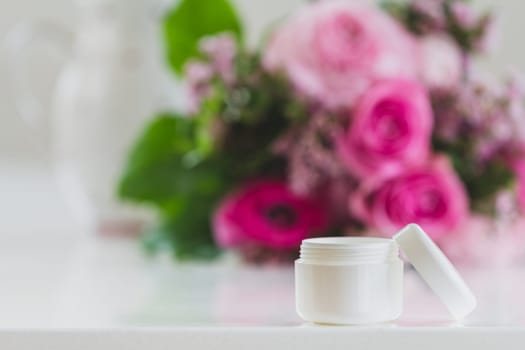 A cream can stands on the table,in the background a great bouquet of flowers that unfolds its beauty. wonderful rose tones are on the table
