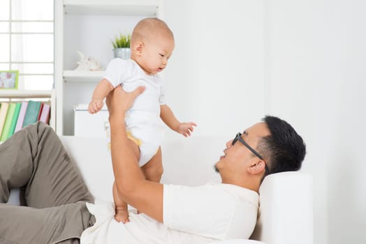 Asian family lifestyle at home. Father playing with baby boy indoors.