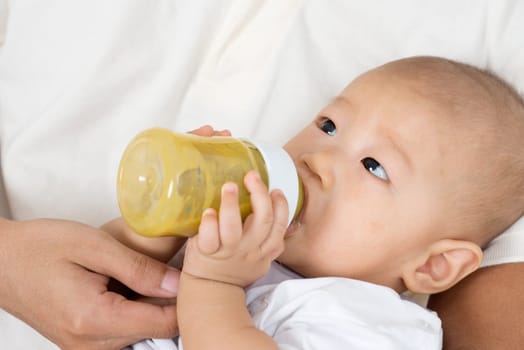 Father bottle feed solid food fruit puree to baby boy, Asian family lifestyle at home.