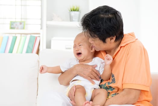 Babysitter comforting crying baby boy at home.