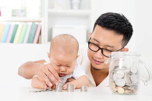 Asian family lifestyle at home. Father and baby counting coins, future education planning concept.
