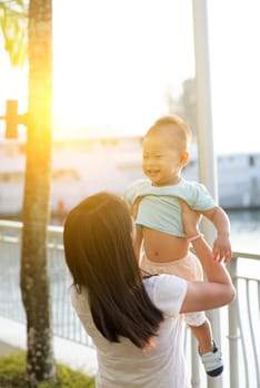 Asian mother and son having fun at outdoor in sunset during holidays.