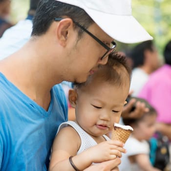 Father and child are eating ice creams on summer holidays. Candid family photo.