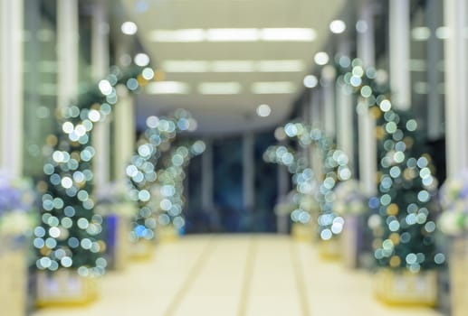 Defocused office, hotel lobby or shopping mall building indoor background with Christmas light illuminated on tree