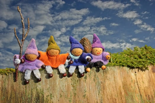 Four little gnomes sit on a tree stump