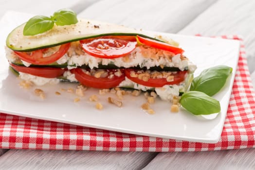 Delicious Italian appetizer of tomato, zucchini slices, nuts, basil and fresh cheese.