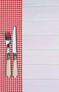 Kitchenware on white and red towel over wooden kitchen table. View from above.