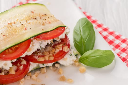 Delicious Italian appetizer of tomato, zucchini slices, nuts, basil and fresh cheese.