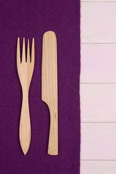Kitchenware on purple towel over wooden kitchen table. View from above.