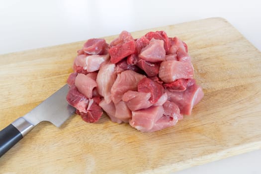Goulash - on a wooden board lies next to a large knife,raw,cut meat
