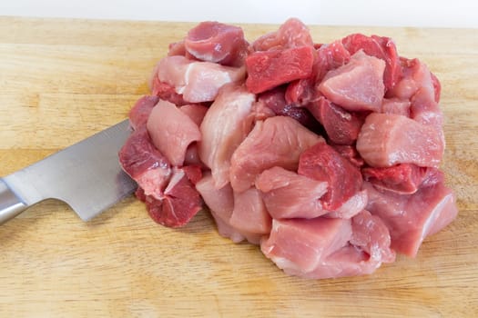 Goulash - on a wooden board lies next to a large knife,raw,cut meat