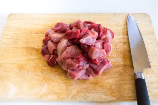 Freshly cut,goulash - cubes of raw pork and beef the big knife is next to it