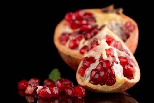 Ripe pomegranate fruit with leaves on black background