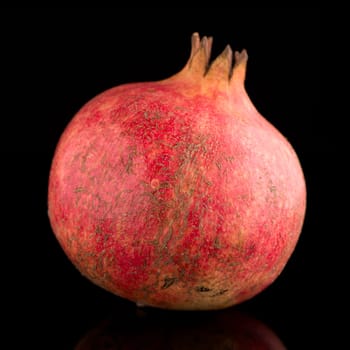 Ripe pomegranate fruit with leaves on black background