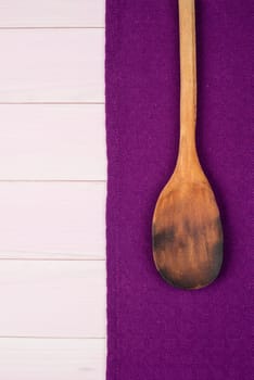 Kitchenware on purple towel over wooden kitchen table. View from above.