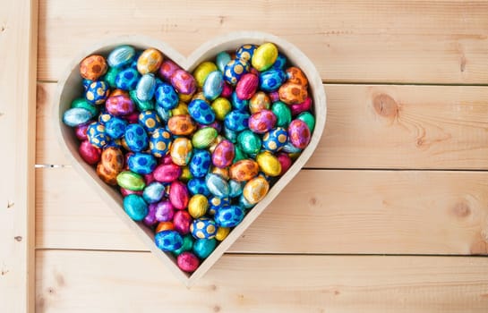 Colorful chocolate eggs on rustic wooden background