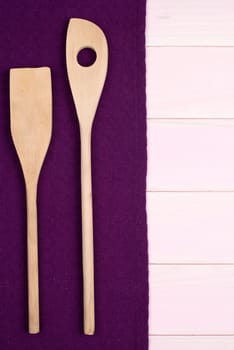 Kitchenware on purple towel over wooden kitchen table. View from above.