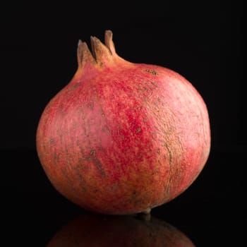 Ripe pomegranate fruit with leaves on black background