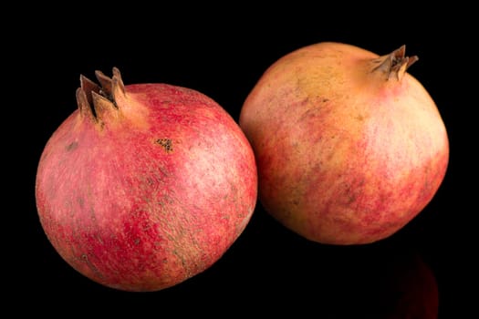 Ripe pomegranate fruit with leaves on black background