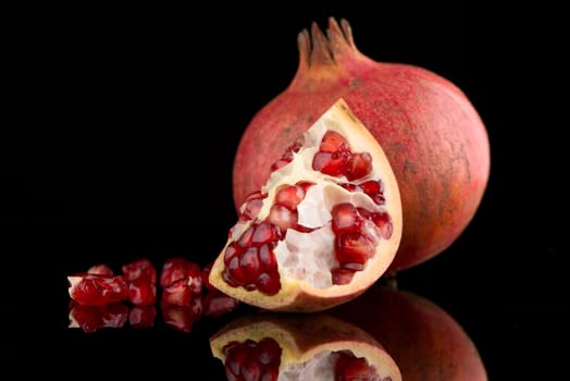 Ripe pomegranate fruit with leaves on black background