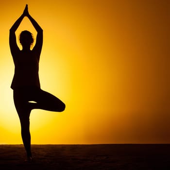 The silhouette of woman practicing yoga in the sunset light