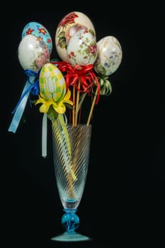Easter eggs handmade with original decorations and colored ribbons. Black background.