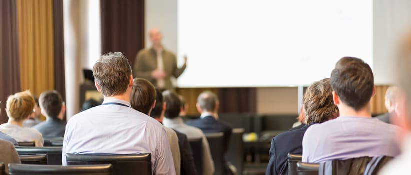 Speaker Giving a Talk at Business Meeting. Audience in the conference hall. Business and Entrepreneurship. Panoramic composition suitable for banners.