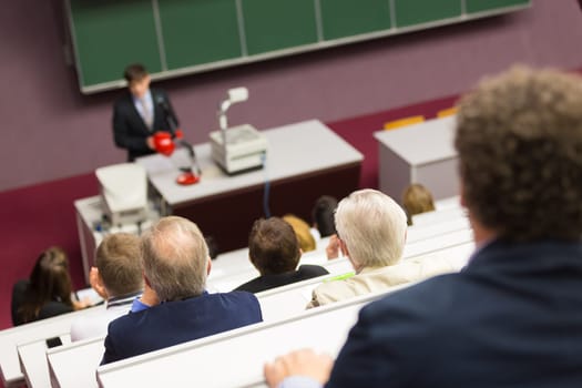 Lecturer at university. Healthcare expert giving a talk to medical faculty professors. Participants listening to lecture and making notes.