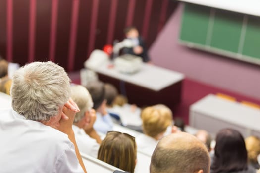Lecturer at university. Healthcare expert giving a talk to medical faculty professors. Participants listening to lecture and making notes.
