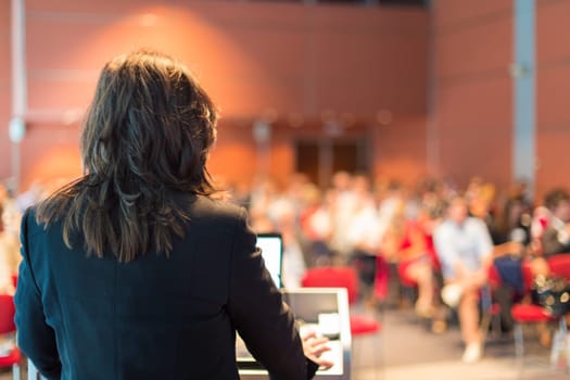 Business woman lecturing at Conference. Audience at the lecture hall.