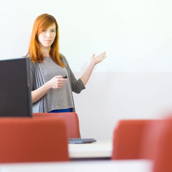 Female speaker giving presentation in lecture hall at university. Copy space for brand presentation.