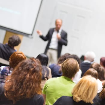 Speaker Giving a Talk at Business Meeting. Audience in the conference hall. Business and Entrepreneurship. Copy space on white board.