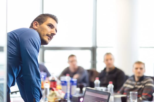 Business man making a presentation at office. Business executive delivering a presentation to his colleagues during meeting or in-house business training, explaining business plans to his employees.