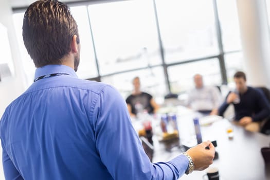 Business man making a presentation at office. Business executive delivering a presentation to his colleagues during meeting or in-house business training, explaining business plans to his employees.