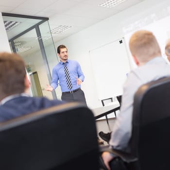 Business man making a presentation at office. Business executive delivering a presentation to his colleagues during meeting or in-house business training, explaining business plans to his employees.