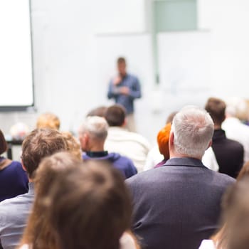 Speaker Giving a Talk at Business Meeting. Audience in the conference hall. Business and Entrepreneurship. Copy space on white board.
