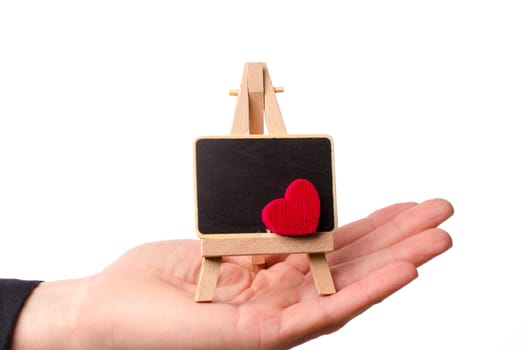 Hand holding a wooden easel with a blackboard and a red heart shape, space for your text